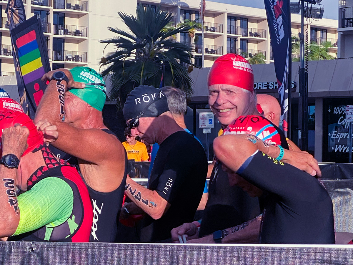 Dr. Leahy and a group of men queuing up in swimsuits and caps getting ready for the swimming portion of the Ironman competition.